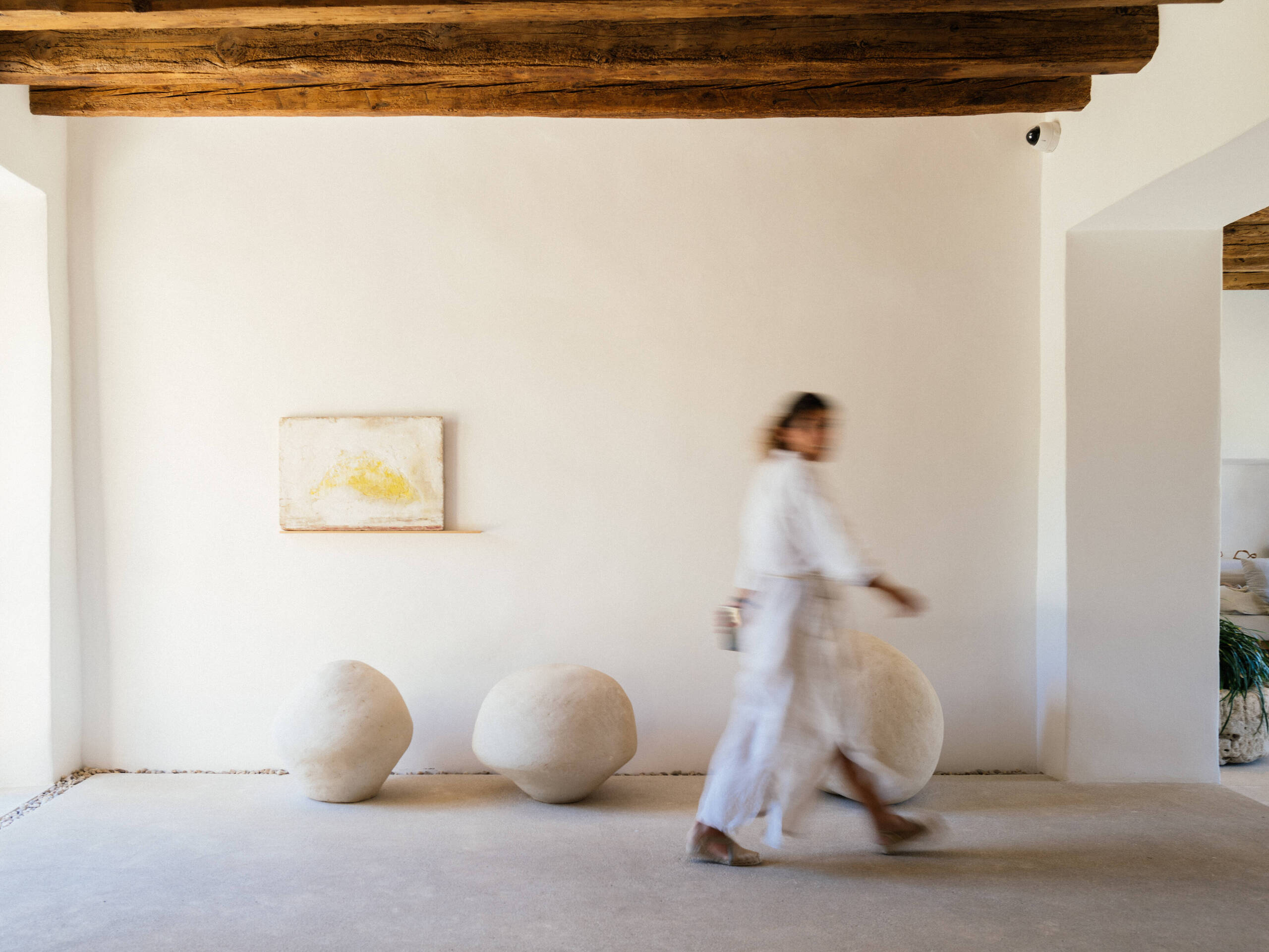 woman walking by a white wall at Es Racó d'Artà wearing all white linen